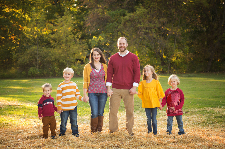Family pictures with two parents and four kids holding hands in a row outside | Senior Photographers in Michigan