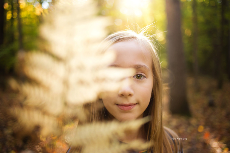 Girl peers through a leaf outside in the woods | Michigan's premier senior photographer 