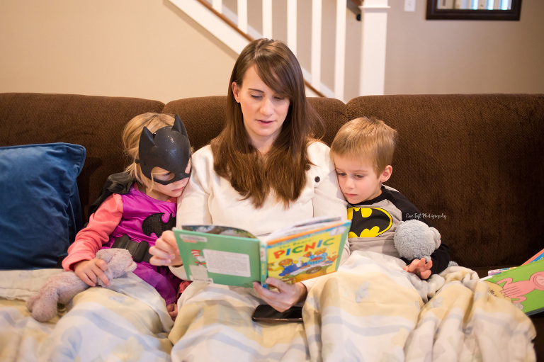 A mother reads books to her two young children on a couch | Midland, Michigan senior photographer