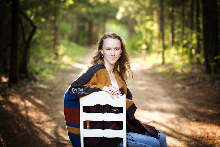 A senior girl sits on a white chair in the middle of City Forest in Midland, Michigan | Senior Photographers in Michigan for their consultation