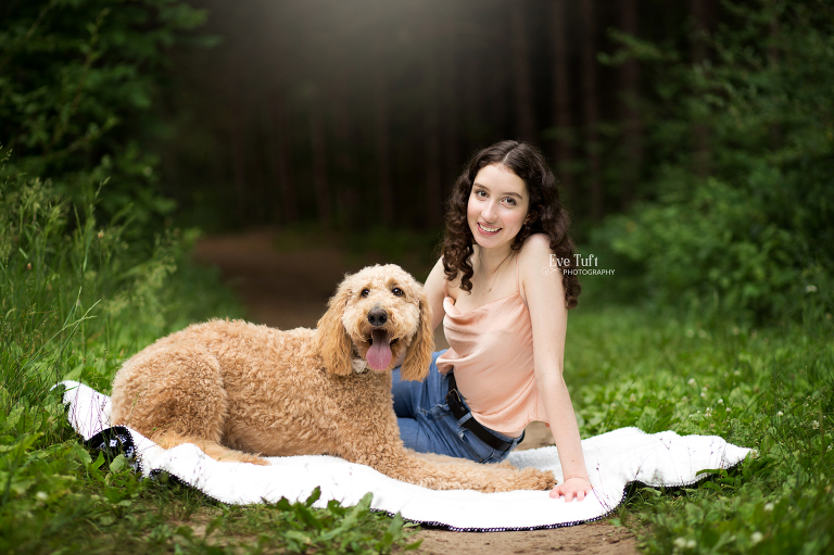 A senior girl sits on a blanket with her dog at City Forest | Senior Photographers in Midland, Michigan