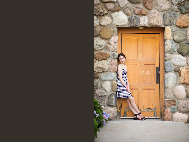 A senior girl leans up against a doorway at the courthouse in Midland, MI for her senior session