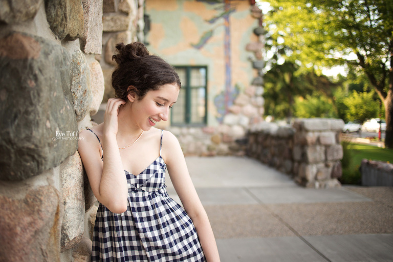 A teenage girl looks off to the side while leaning against the courthouse building in Midland, Michigan | Senior Photographers near me