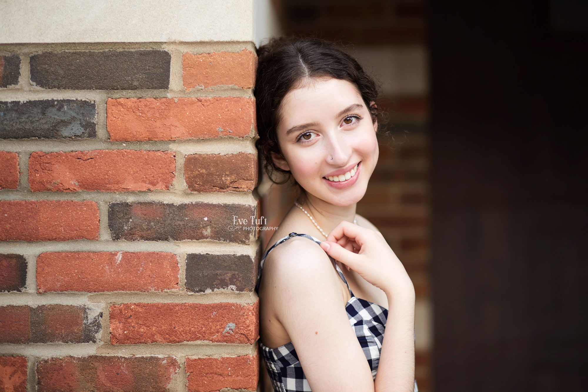 A teenage girl leans up against a brick wall in Midland, Michigan | Senior Photographers in Midland