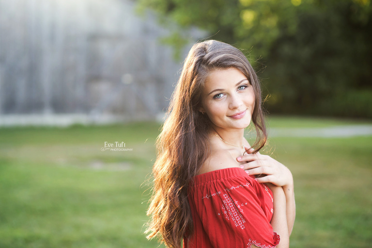 A senior girl stands in front of a wooden barn at the Chippewa Nature Center in Midland, Michigan | Senior Photographers near me