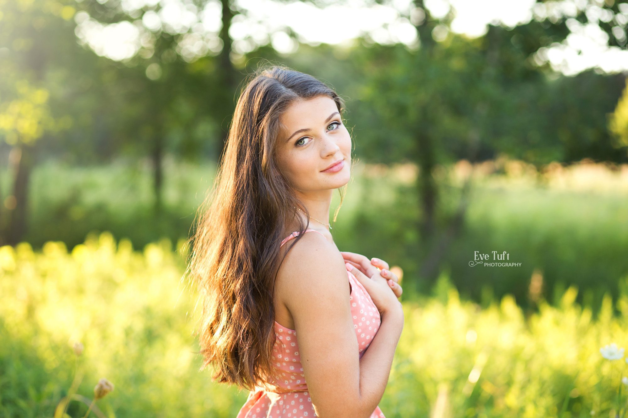 A beautiful teenage girl stands in a field with the light at her back | Midland, Michigan senior photographer