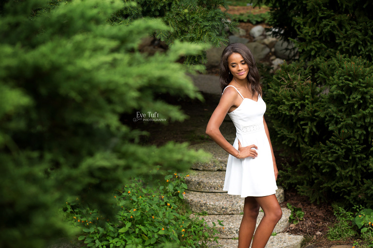 Beautiful senior girl poses on stairs outside by trees at Dow Gardens | New Locations for senior sessions in Midland