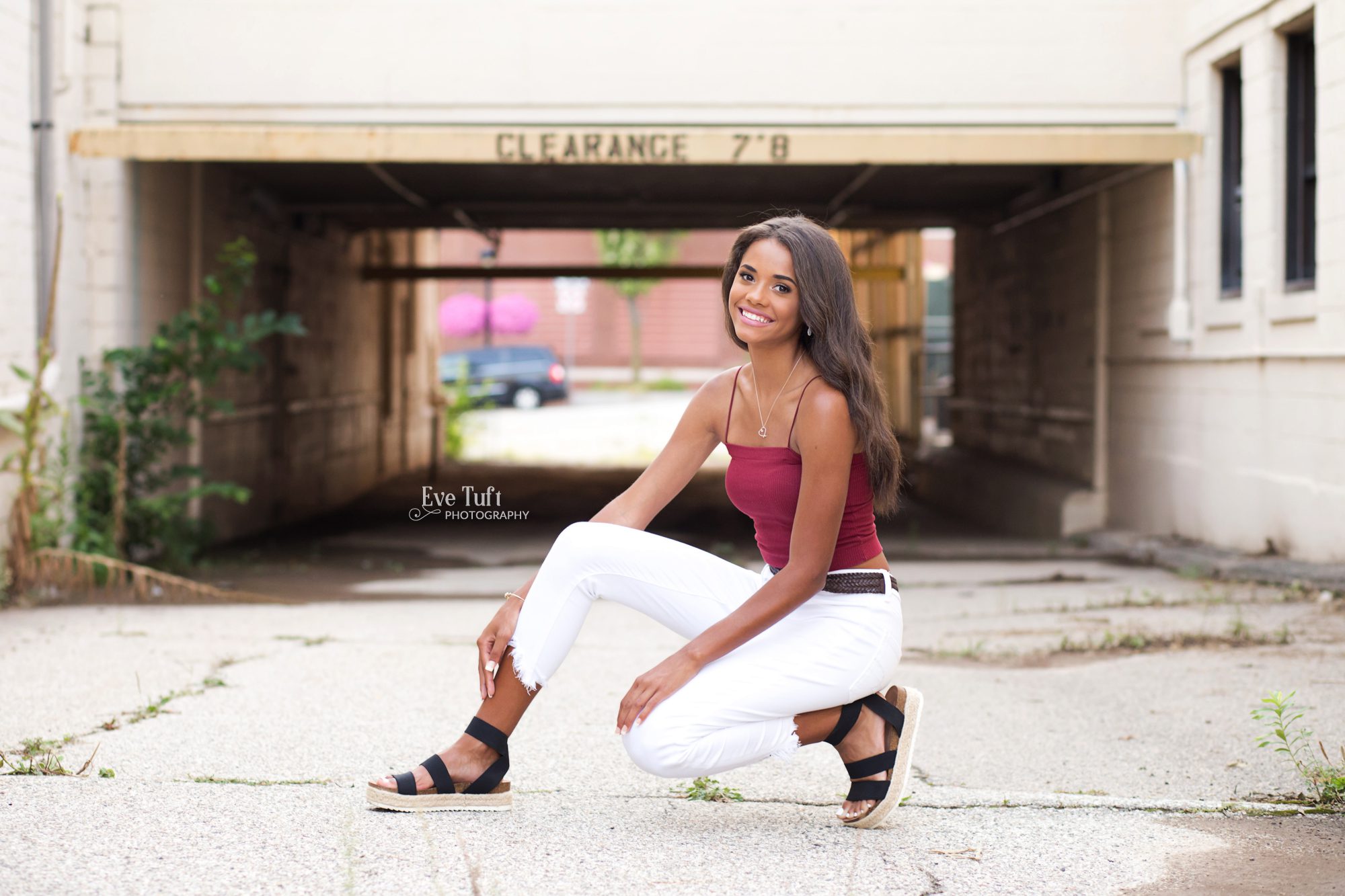 A senior girl crouches down in an alleyway in an urban location | Senior Photographer in Midland, MI