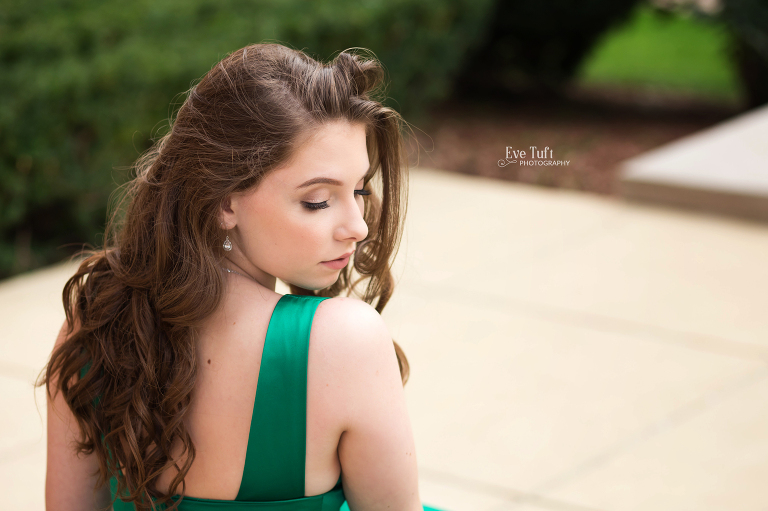 A senior girl looks over her shoulder while sitting on church steps outside in her prom dress | Michigan Senior Portrait Photographer