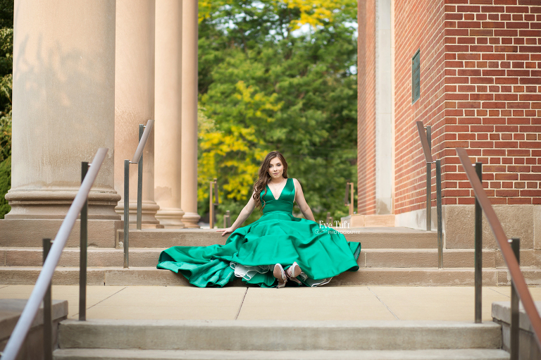 A beautiful teenager sits outside a church in her green prom dress | Midland, MI senior photographer