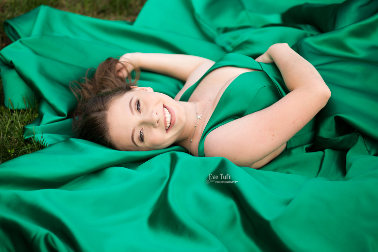 A beautiful teenager lies down in the grass with her dress underneath her | H.H. Dow High School Photographer in Midland, MI