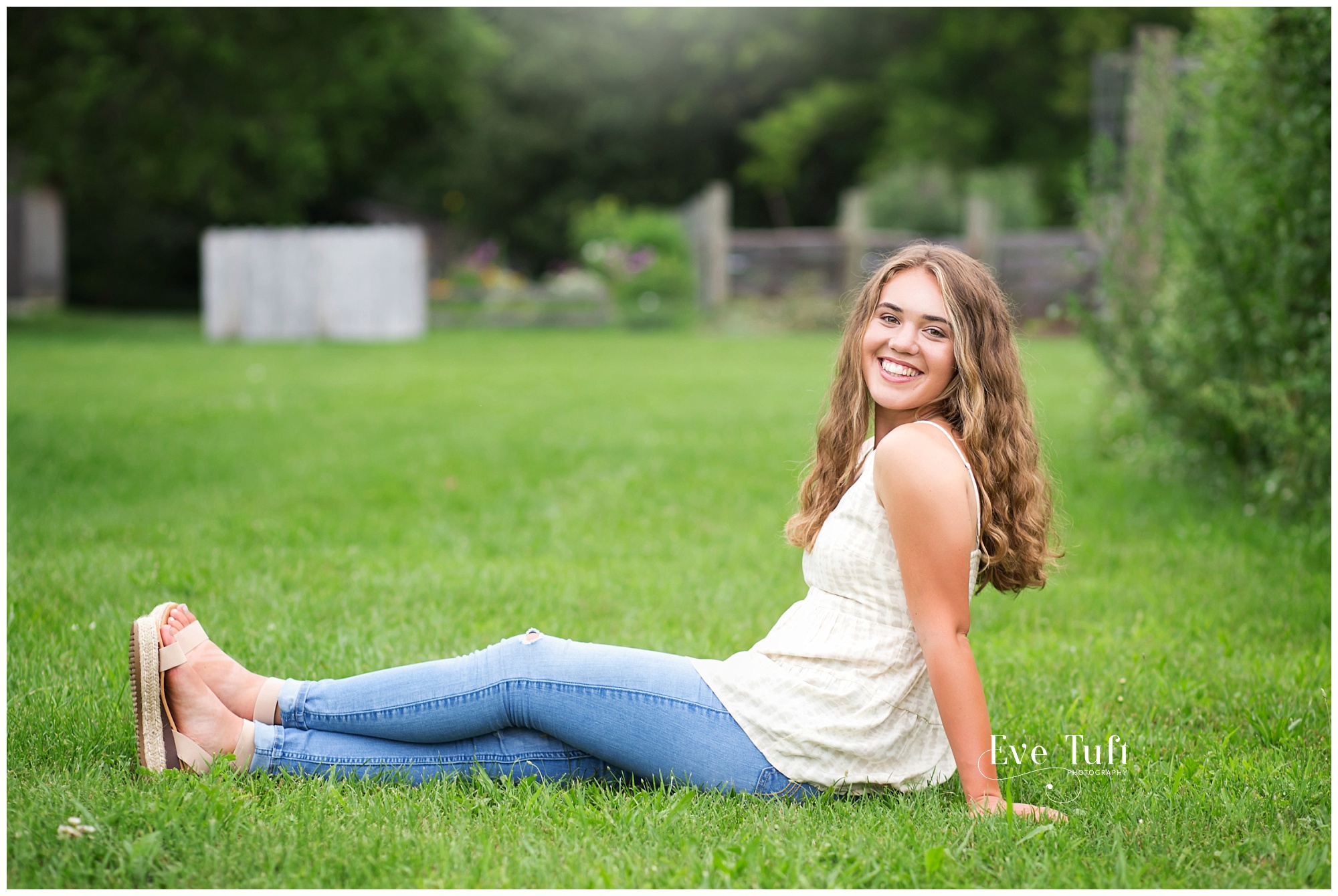 A teen sits in the grass outside for her session | Senior Photographer in Midland, Michigan