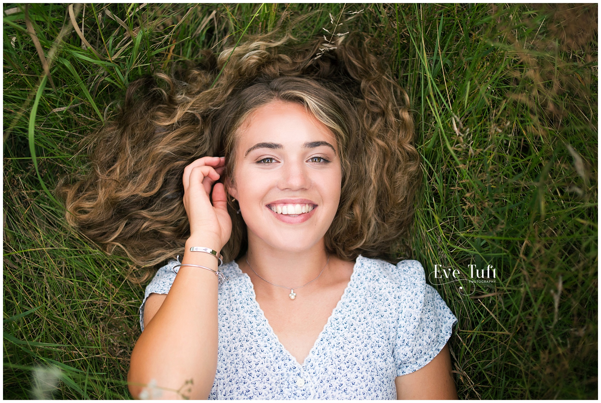 A teen lies on her back outside in the grass | Senior session in Midland, MI