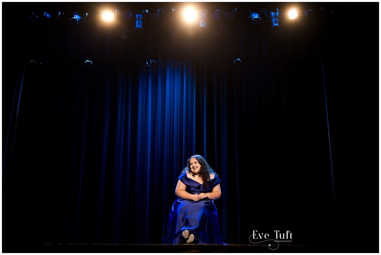 A teen laughs on stage in the theater for her session | Senior Photographer, Midland, MI