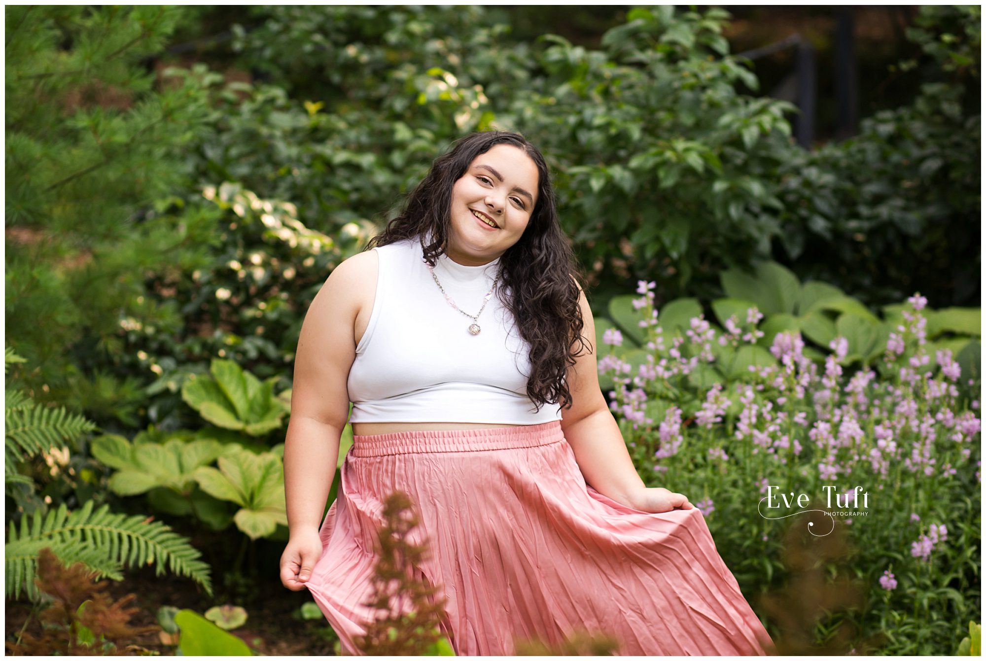 A teen twirls outside in a flower bed | Dow Gardens Senior Session