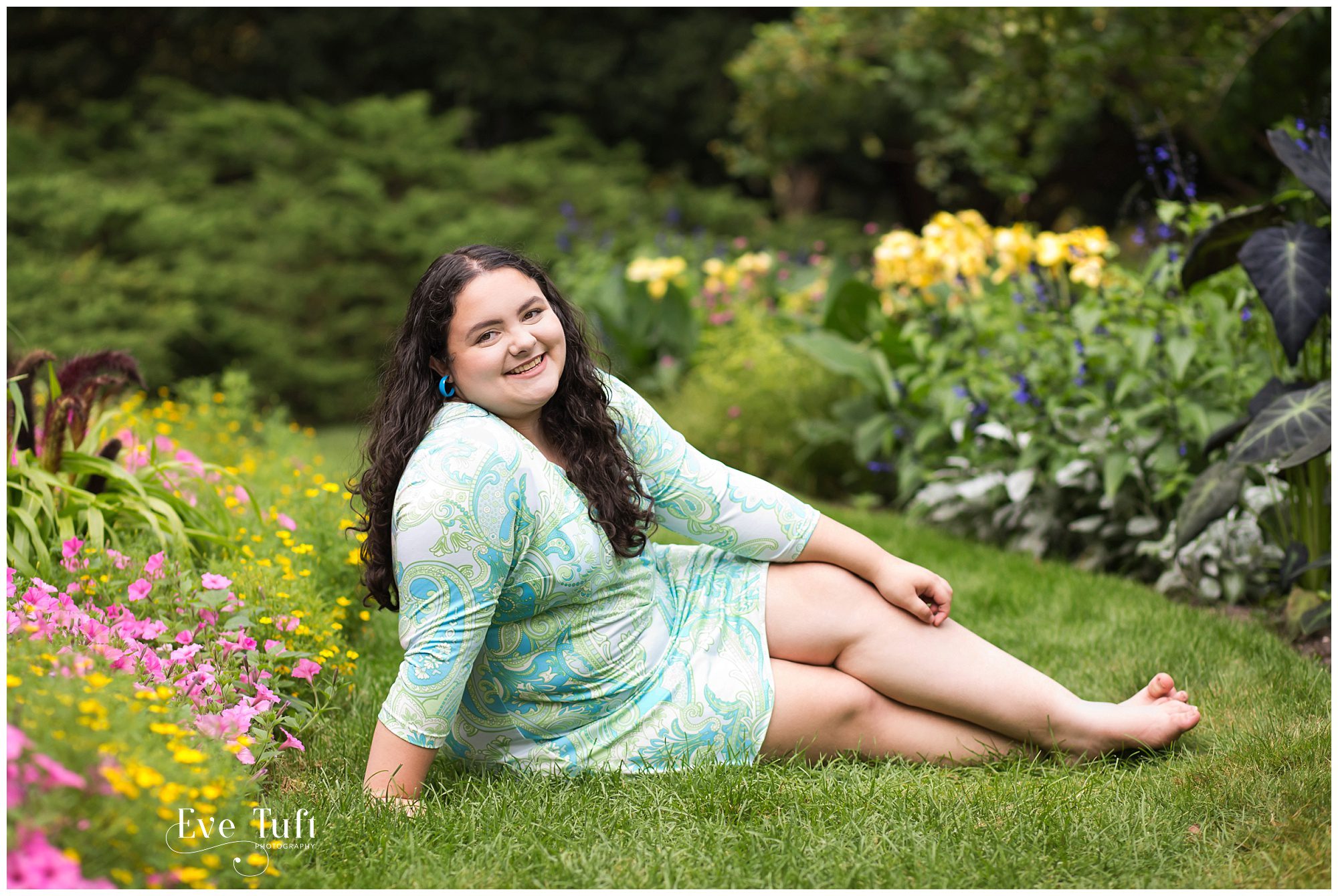 A teen lies on the grass near flower beds | Senior Photographer in Midland, Michigan