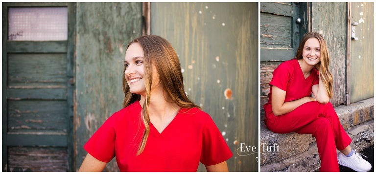 A teenager in red scrubs smiles in front of an old building | Senior Photographer in Bay City, Michigan