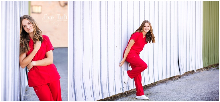 A teen girl in hospital scrubs leans against a white wall outside for her session | Senior Photographers in Bay City, Michigan