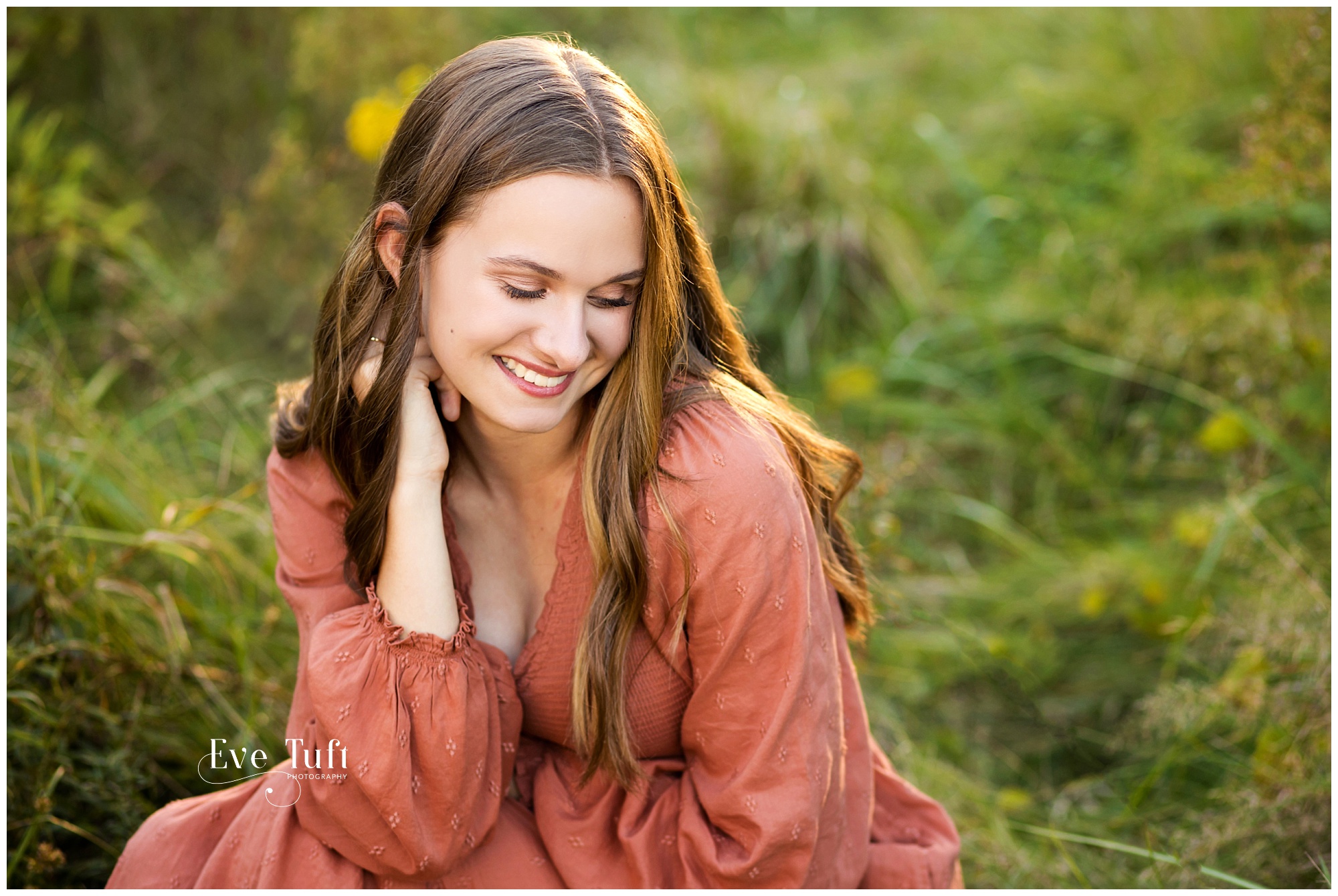 A beautiful teen girl sits in a field of grass outside at the nature center | Midland, Michigan Senior Photographer