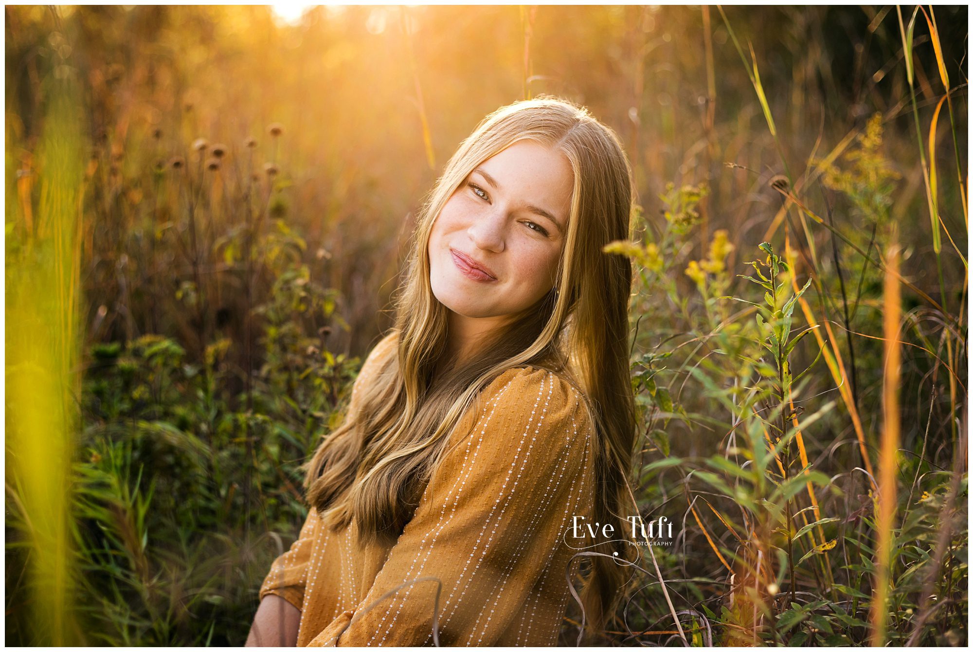 A senior girl sits in the flowers outside | Senior Session at the Chippewa Nature Center