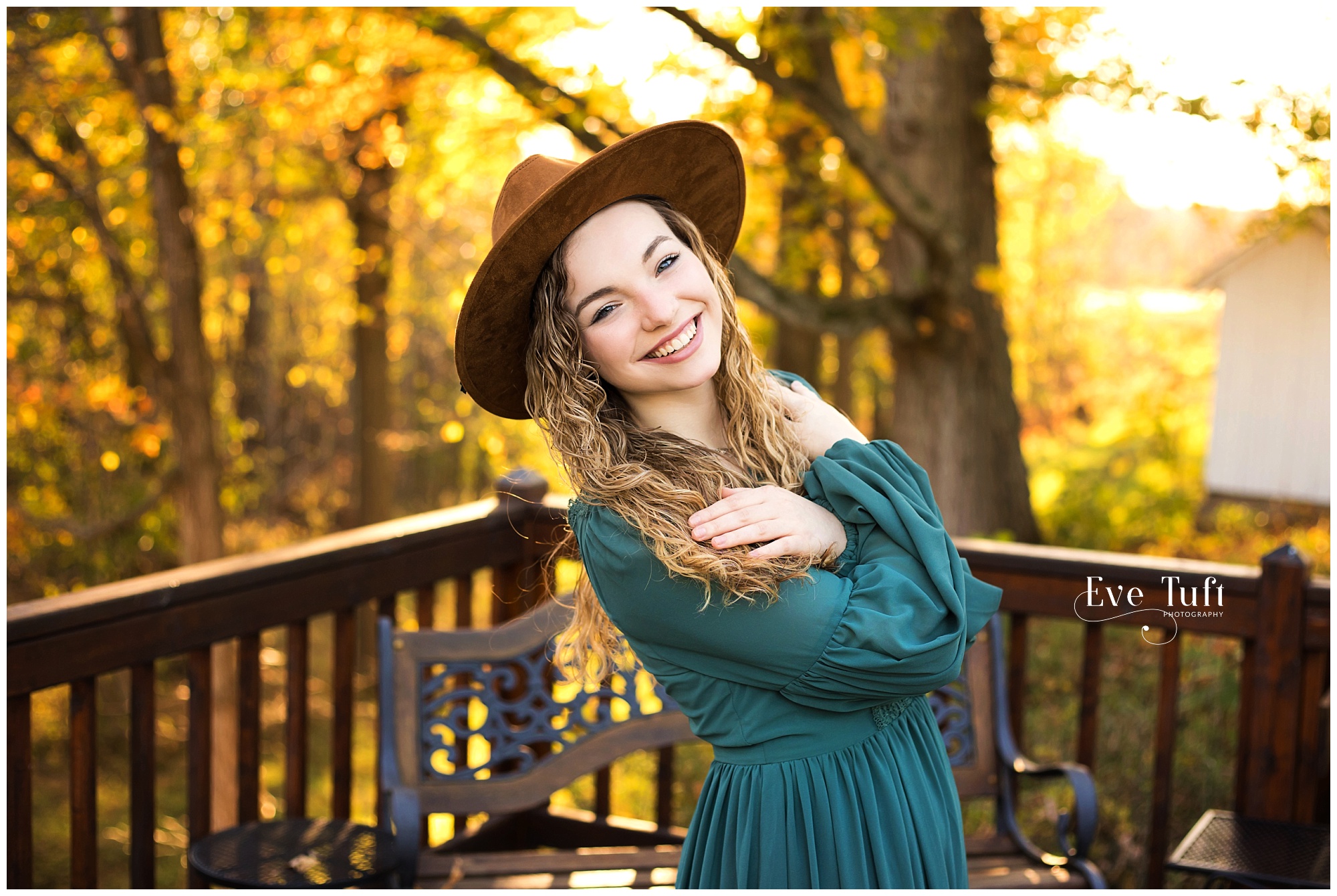 A beautiful teen leans back on the porch with the fall colors outside | Senior Photographer in Gladwin, Michigan