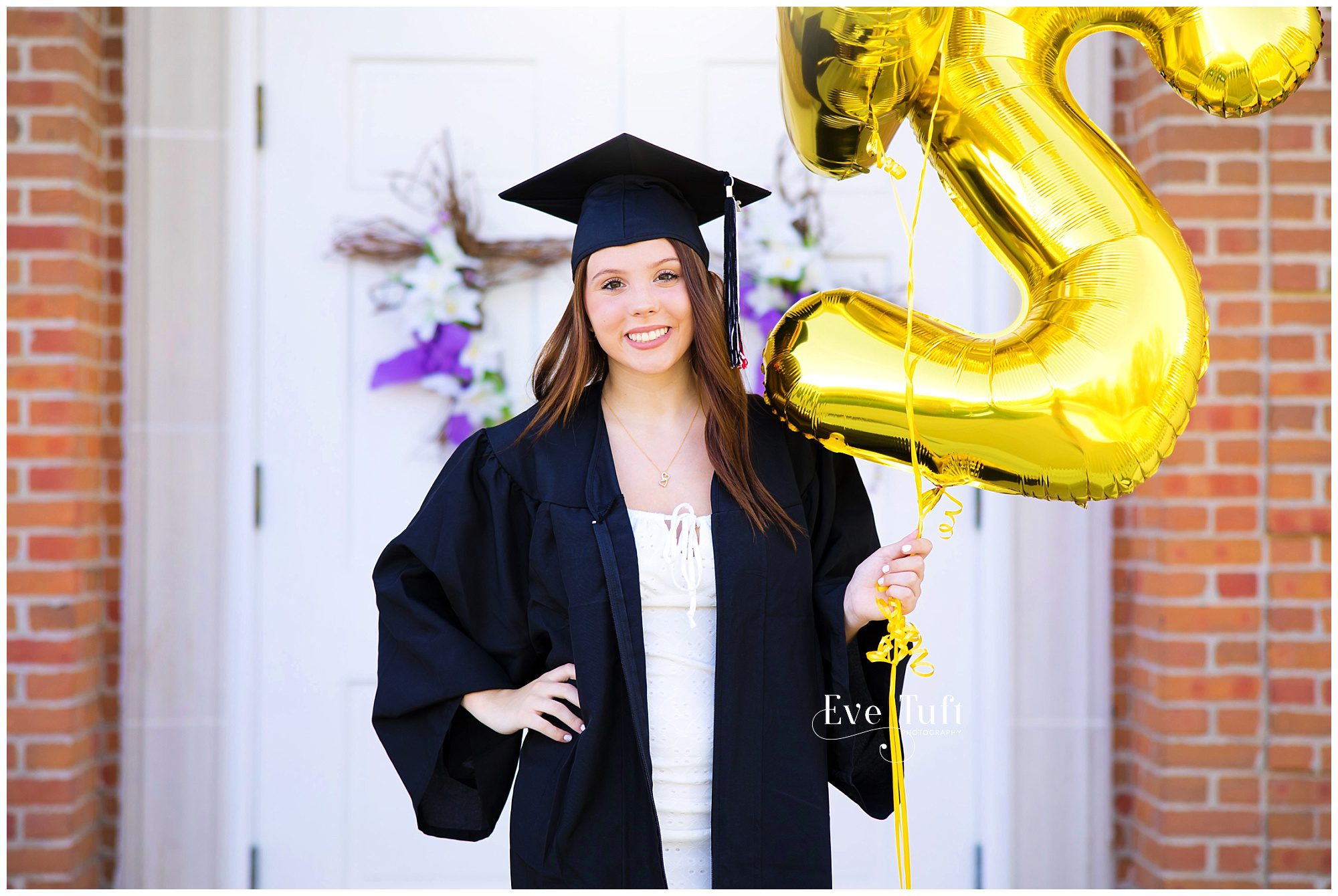 A senior holds a bouquet of balloons at her cap and gown session outside | Senior Photographer in Midland, Michigan