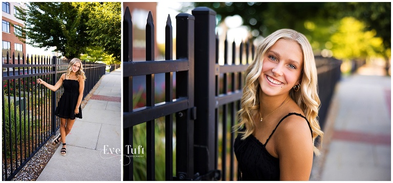Emily holds onto a fence outside in Downtown | Bay City, MI Senior Photographer